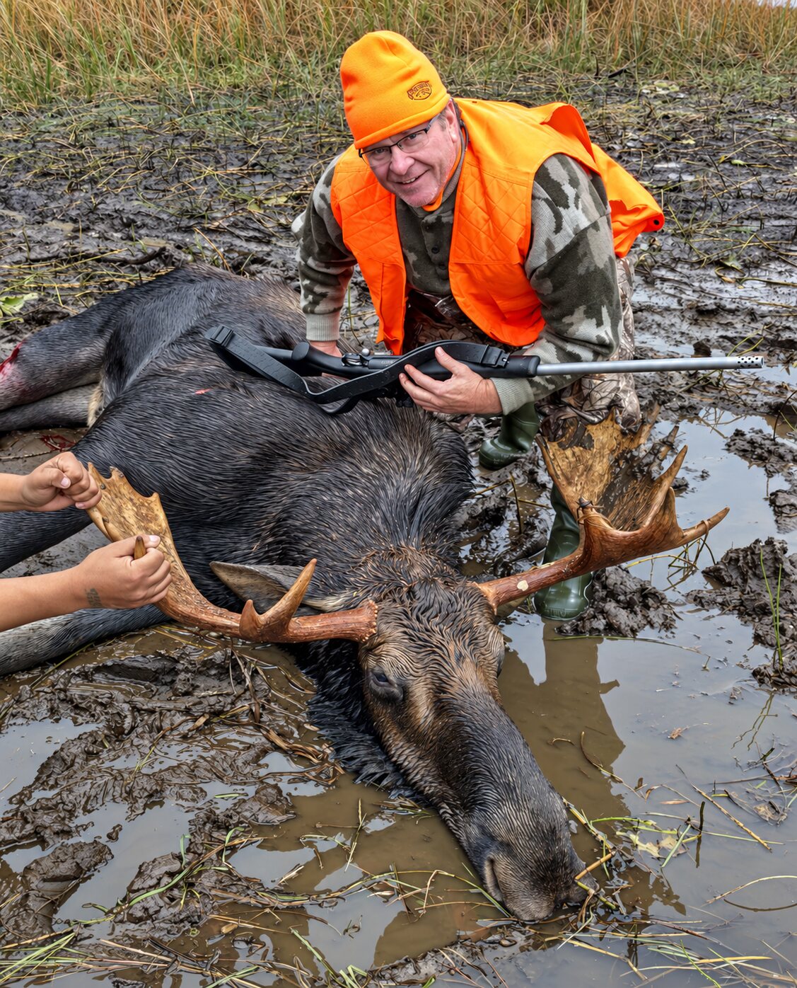 Hunter with a harvested bull moose after a long shot across the river from a Wesley's Outposts cabin