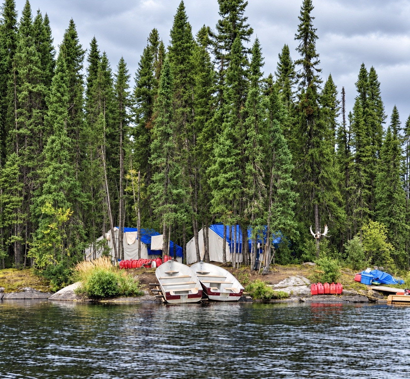 Wesley's lakeside tent camp with canvas tents beneath spruce trees and two boats on shore